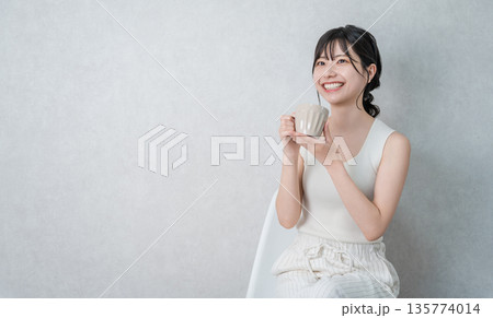 マグカップでホットドリンクを飲み温活するタンクトップ姿の若いアジア人女性 マグカップでホットドリンクを飲み温活するタンクトップ姿の若いアジア人女性 135774014