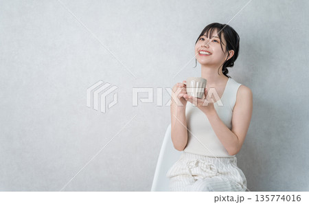 マグカップでホットドリンクを飲み温活するタンクトップ姿の若いアジア人女性 マグカップでホットドリンクを飲み温活するタンクトップ姿の若いアジア人女性 135774016