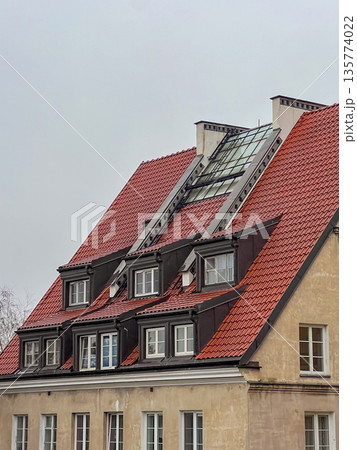 Building with red roof and glass feature in cloudy weather in urban area 135774022