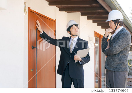 家の前で打ち合わせをするスーツの男性たち 135774605