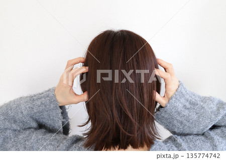 頭を抱える女性の後ろ姿 135774742