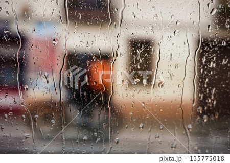 Rain drops on window with blurred city background 135775018