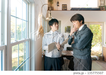 室内の窓を確認する作業服の男性 135775507