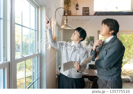 室内の窓を確認する作業服の男性 135775510