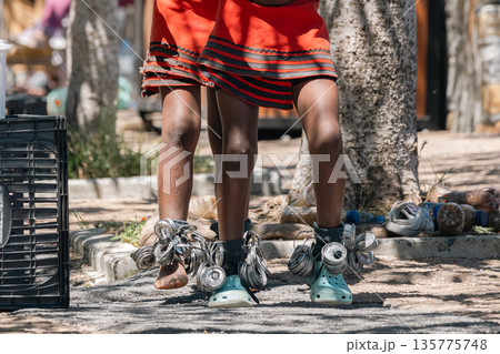 African child wearing traditional skirt and ankle shakers made from recycled cans, celebration and culture. 135775748