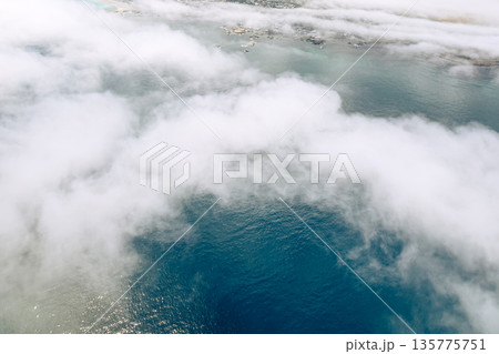 Aerial view of clouds over blue ocean and distant land. Helicopter tour experience in Cape Town, South Africa, for luxury travel for vacation. 135775751