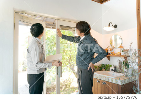 ガラス扉の前で打ち合わせする作業服の男性 ガラス扉の前で打ち合わせする作業服の男性 135775776