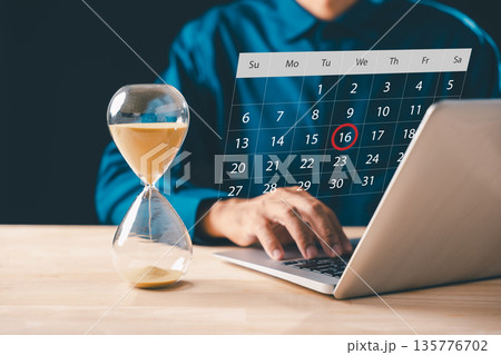 Hourglass time glass and flowing sand symbolize business urgency, growth, countdown to deadline, professional uses laptop optimizing tasks on calendar showing important project date Hourglass time glass and flowing sand symbolize business urgency, growth, countdown to deadline, professional uses laptop optimizing tasks on calendar showing important project date 135776702