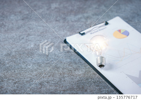 Light bulb business career creative manager innovation concept energy accountant ideas accounting rests on financial report papers on office clipboard over stone desk surface Light bulb business career creative manager innovation concept energy accountant ideas accounting rests on financial report papers on office clipboard over stone desk surface 135776717