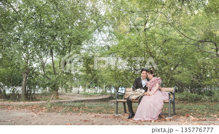 公園のベンチでウェディングフォトを撮るカップル 公園のベンチでウェディングフォトを撮るカップル 135776777
