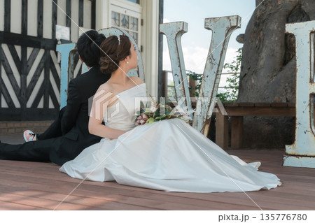 LOVEのオブジェの前でウェディングフォトを撮る新郎新婦 135776780