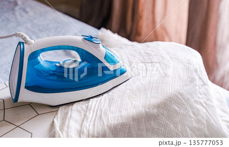 Ironing desk and iron in the room Ironing desk and iron in the room 135777053