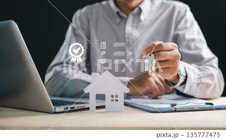 Man holding house keys, symbol of real estate home property purchase, seeking mortgage loan financing, reviewing documents for new acquisition, investment using laptop, ensuring quality property 135777475