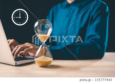 Hourglass time glass sand clock displays business urgency concept, timer for optimize growth, person works on laptop for important deadline countdown 135777483