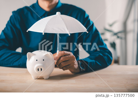 Piggy bank money protect financial insurance concept risk umbrella, man holds small white umbrella over ceramic bank on wooden table to show finance safety security collage savings Piggy bank money protect financial insurance concept risk umbrella, man holds small white umbrella over ceramic bank on wooden table to show finance safety security collage savings 135777500