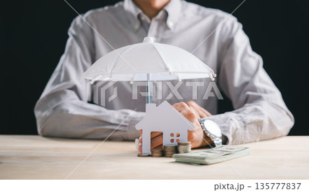 Property protection concept with small house and umbrella shielding home, financial security for house insurance, coins and money demonstrate wealth preservation against risks Property protection concept with small house and umbrella shielding home, financial security for house insurance, coins and money demonstrate wealth preservation against risks 135777837