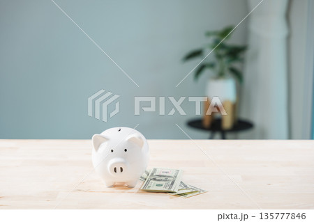 Piggy bank money shows global economy finance stock growth business concept, save, invest, economic stability on wooden table with white ceramic for secure future wealth planning Piggy bank money shows global economy finance stock growth business concept, save, invest, economic stability on wooden table with white ceramic for secure future wealth planning 135777846