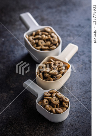 Dry kibble pet food. Dog or cat food in scoop on black table. 135779933