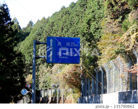 秋の国道沿いに立つ方面案内板 135780662