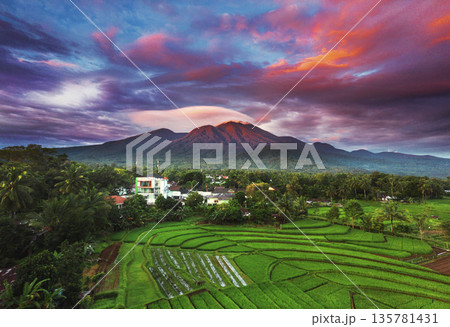 the view of the morning sunrise in the village of Kemumu, with the sky turning red over the mountain ranges and green rice fields the view of the morning sunrise in the village of Kemumu, with the sky turning red over the mountain ranges and green rice fields 135781431