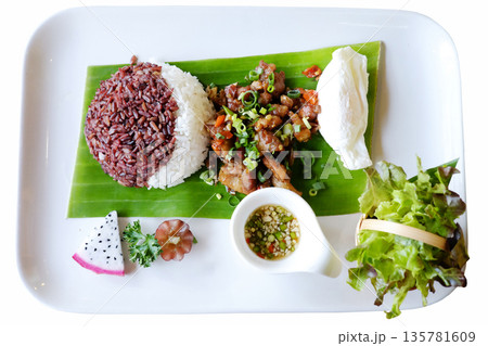 Top view of brown rice berry stir-fried boiled eggs with basil and vegetables on fresh banana leaf on white dish isolated white background with clipping path 135781609
