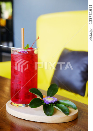 A glass of red soda with a cherry and violet flower decorated on topping on wwoden table 135781611