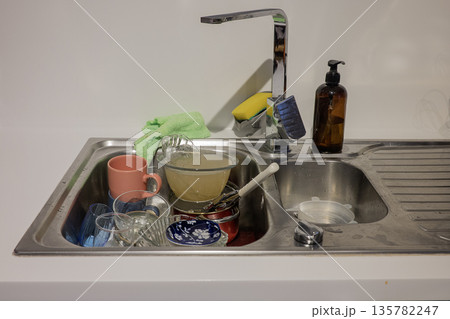 Dirty dishes in sink on the kitchen Dirty dishes in sink on the kitchen 135782247