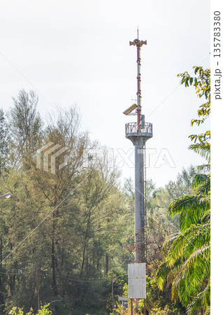 A tower with a tsunami or emergency warning system in the coastal area in Thailand. Observation deck with loudspeakers in the trees to monitor the situation. High quality photo 135783380