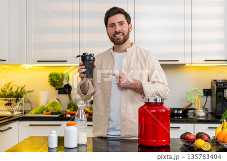 Middle-aged man mixing protein shake in kitchen smiling for fitness diet nutrition workout at home Middle-aged man mixing protein shake in kitchen smiling for fitness diet nutrition workout at home 135783404