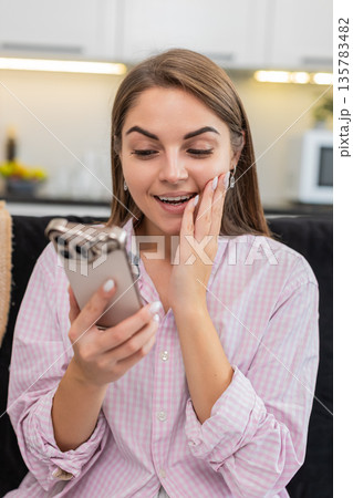Young woman reacts wow eyes wide holding smartphone to positive big surprise and news about game win Young woman reacts wow eyes wide holding smartphone to positive big surprise and news about game win 135783482