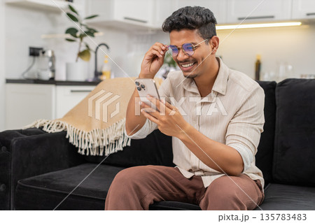 Indian man puts on glasses to read long small text on smartphone sharp vision returns continues chat Indian man puts on glasses to read long small text on smartphone sharp vision returns continues chat 135783483