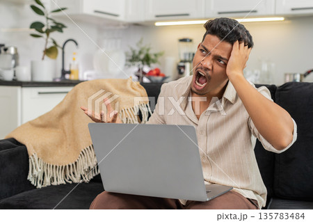 Indian man reads rejection on laptop holds head breathes deep builds step plan to improve work clear Indian man reads rejection on laptop holds head breathes deep builds step plan to improve work clear 135783484