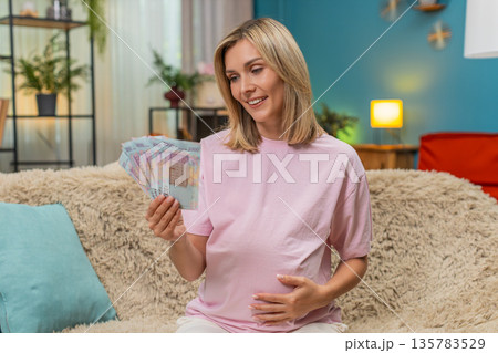 Pregnant woman counting UAH Ukrainian hryvnia cash money planning budget for childbirth financial Pregnant woman counting UAH Ukrainian hryvnia cash money planning budget for childbirth financial 135783529