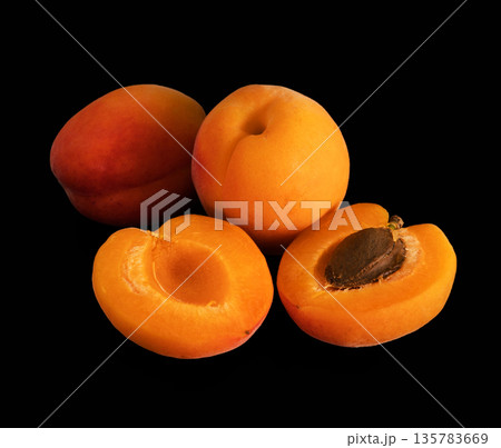 Ripe apricot, whole and in parts, on a black background, isolated 135783669