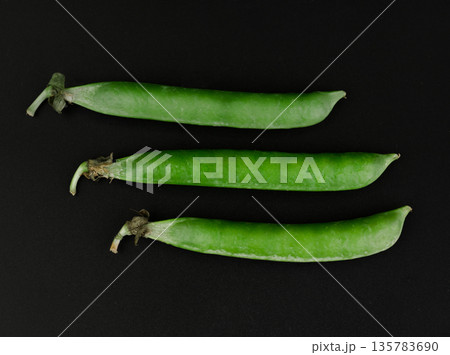 Three whole pea pods on black background isolated 135783690