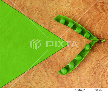 Green peas, in an open pod on a wooden board, space for the text 135783692