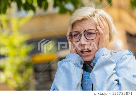 Sad unhappy young woman thinks over life concerns, suffers from unfair situation on city street Sad unhappy young woman thinks over life concerns, suffers from unfair situation on city street 135783871