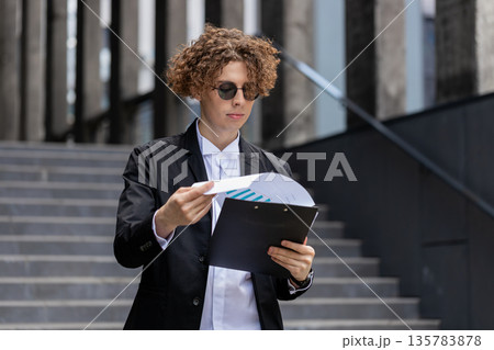 Happy businessman work with documents reading information business papers prepare financial report 135783878