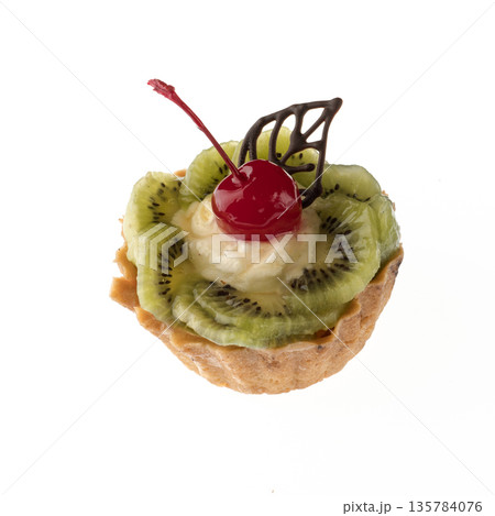 Dessert, cake with kiwi and cherries, on a white plate isolated 135784076