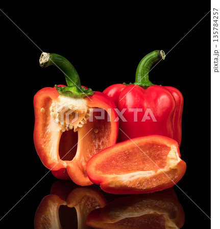 Sweet peppers, red, whole and cut into pieces, on a black background, with reflection Sweet peppers, red, whole and cut into pieces, on a black background, with reflection 135784257