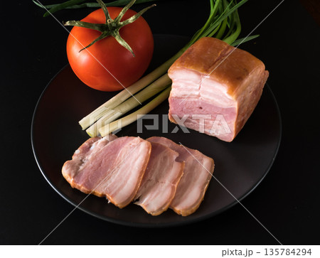 Food, Sliced bacon, tomato green onion, on a black plate on a black background Food, Sliced bacon, tomato green onion, on a black plate on a black background 135784294
