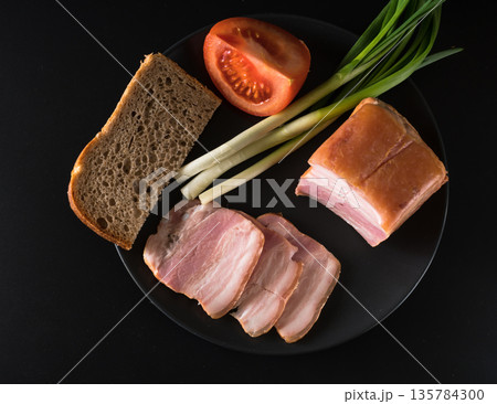 Food, lard, green onions, tomato, black bread, on a black plate on a black background 135784300
