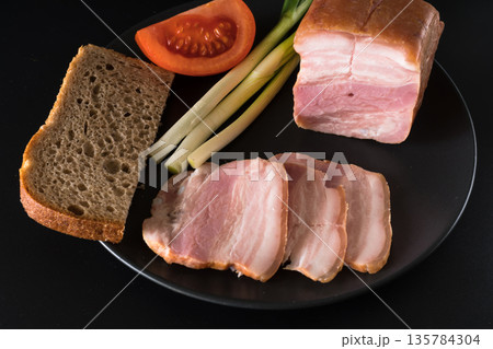 Food, lard, green onions, tomato, black bread, on a black plate on a black background 135784304