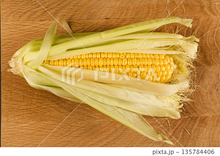 Kachan of young corn, in husks on a wooden board 135784406