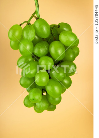 Bunch of grapes of white filling, on a yellow background Bunch of grapes of white filling, on a yellow background 135784448