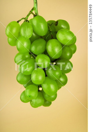 a bunch of ripe grapes, white filling, on a yellow background a bunch of ripe grapes, white filling, on a yellow background 135784449