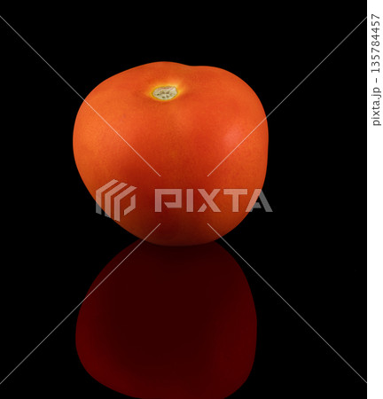 One ripe tomato on a black background with reflection One ripe tomato on a black background with reflection 135784457