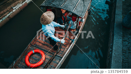 Charming boatman steering through serene waters in a traditional canoe. Zhujiajiao, Shanghai, China 135784559