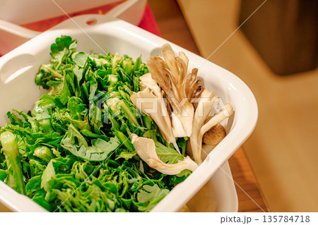 白いざるに入った新鮮な春菊と舞茸の接写 135784718