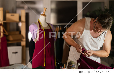 Man tailor repairs clothes, provides services for restoration of damaged cloth Man tailor repairs clothes, provides services for restoration of damaged cloth 135784871